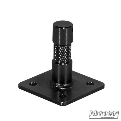 A black metal baby nail on a plate, used for mounting purposes in film sets or production environments.